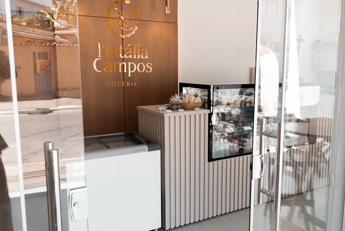Balcão e vitrine da doceria vistos pela porta de vidro