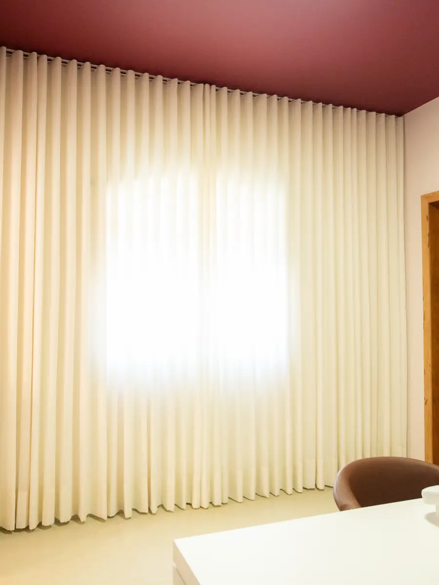 Parede inteira de cortina de linho natural em ondas, iluminada pela luz da janela