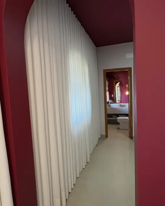 Corredor com arco bordô e cortina de linho natural iluminada pela janela, em uma entrega da VestiLar